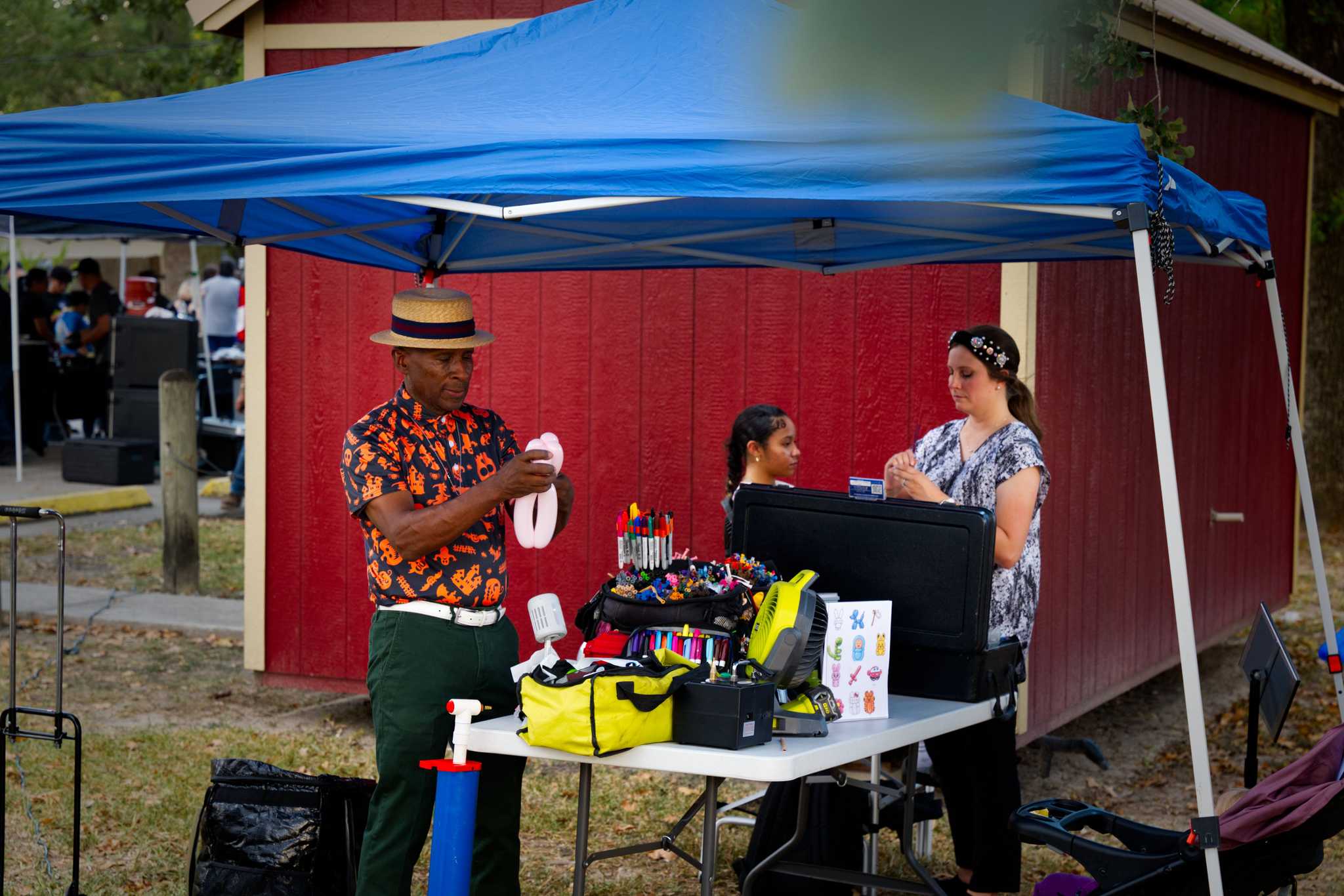 A man creating balloon animals and a woman face painting.