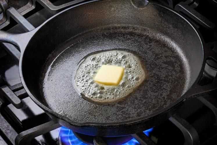 Butter melting in a cast iron pan over a gas stove