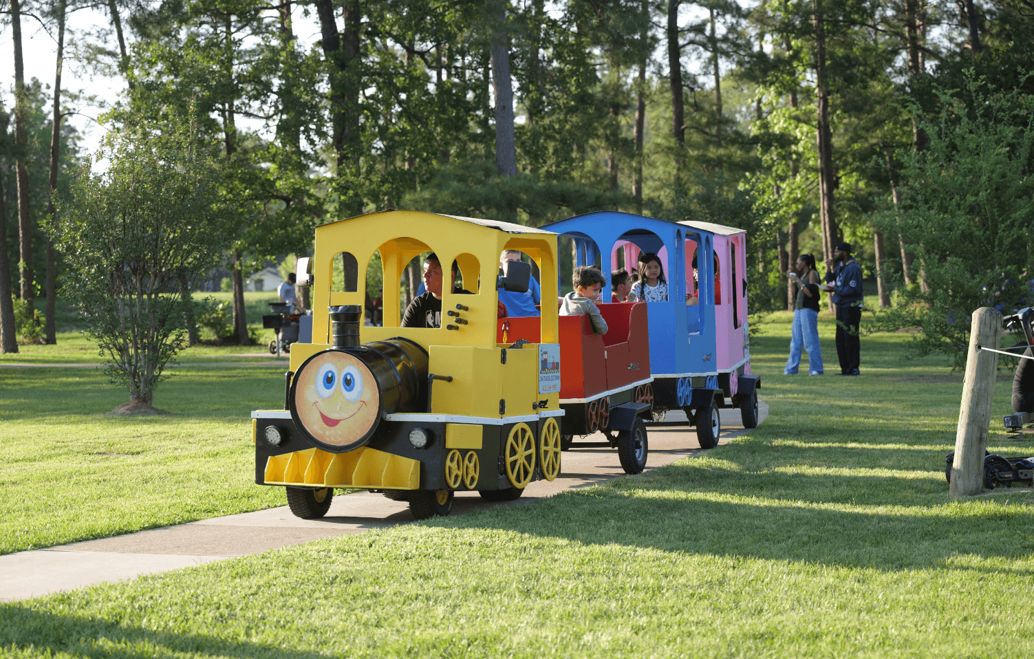 a train with children riding along the sidewalk